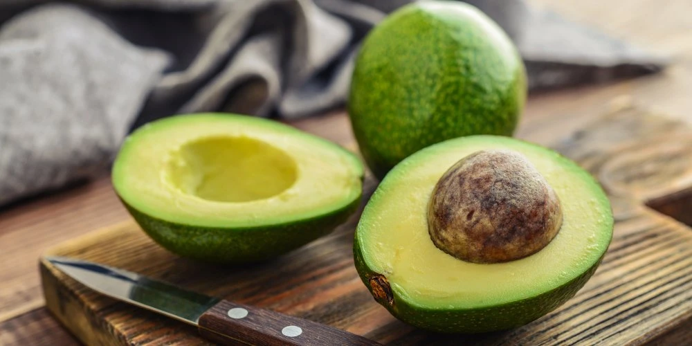 Un avocat coupé en deux, révélant sa chair crémeuse et son noyau, symbole de beauté naturelle.