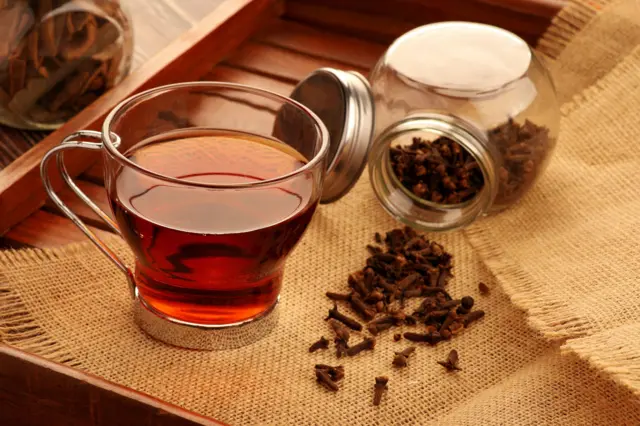 Clous de girofle et tasse sur une table en bois