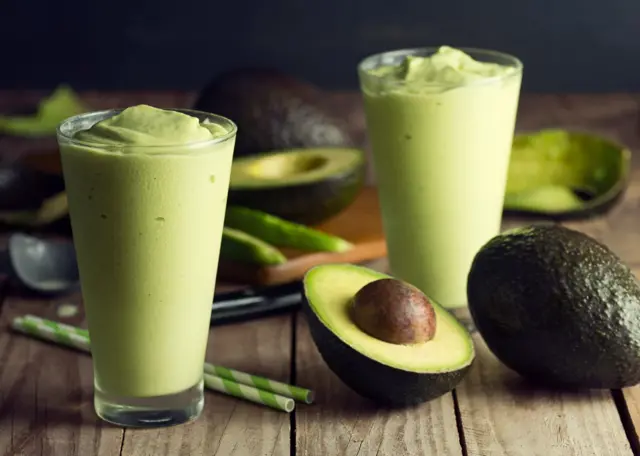 Avocat entier et tranché sur une planche en bois