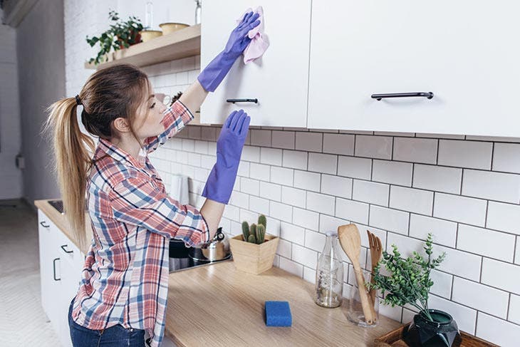 Femme en train de nettoyer des armoires de cuisine 