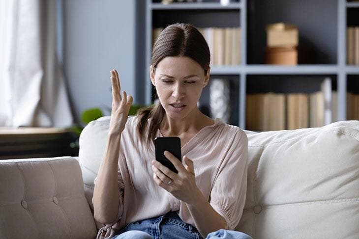 Femme tenant un téléphone, l’air dépité