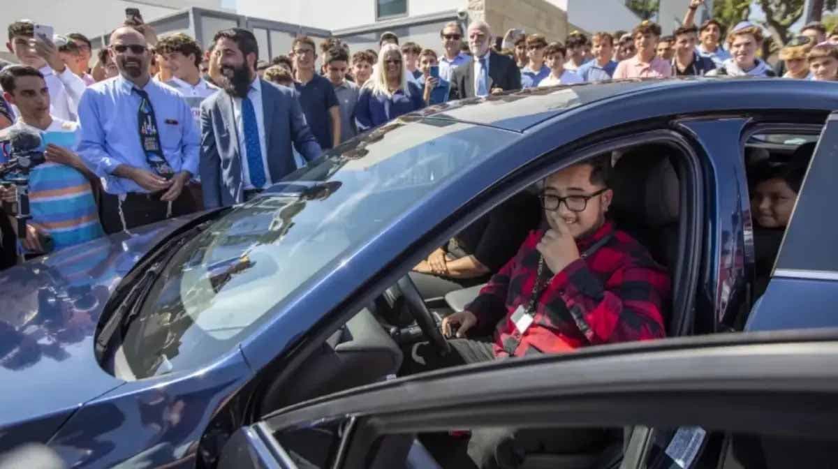 Julio Castro, assis au volant d’une voiture avec tous les étudiants et le staff académique qui l'entourent