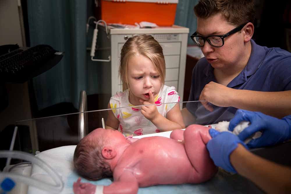 Le papa présente le bébé à sa grande sœur