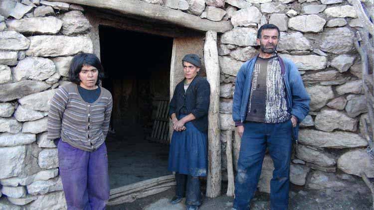 Photo de deux femmes et un homme devant la porte de la maison en pierre