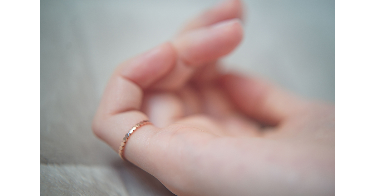 Une main féminine portant une bague fine à l'auriculaire