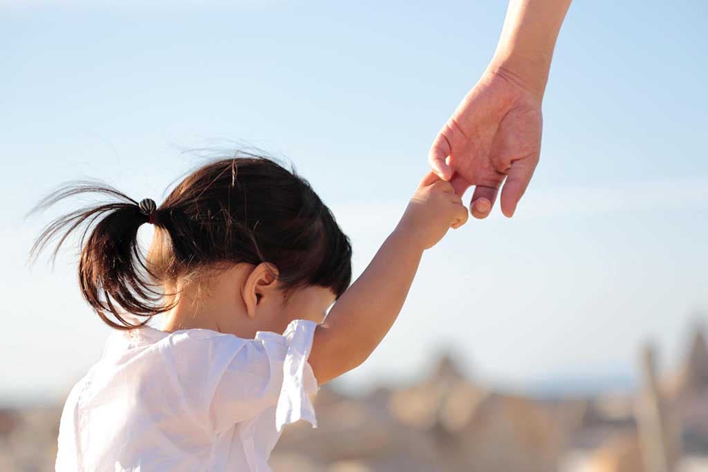 Une maman qui tient la main de sa fille