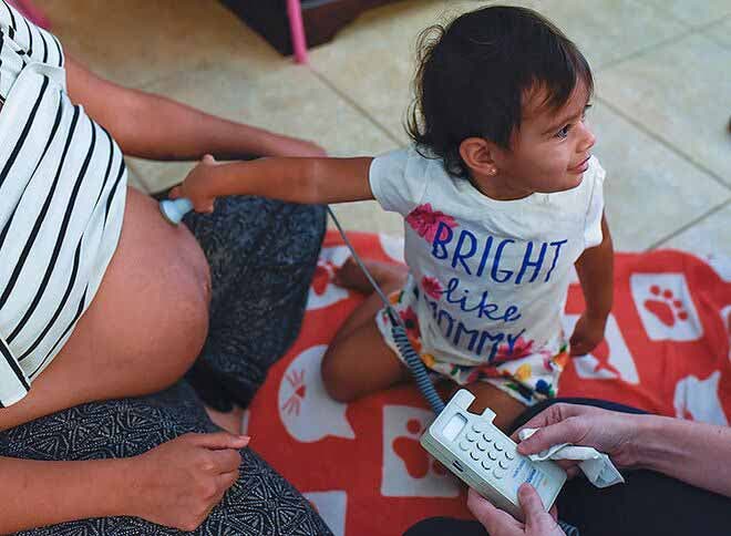 Une petite fille touche le ventre de sa maman enceinte