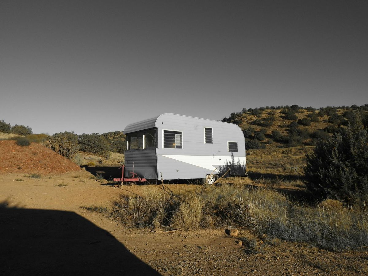Une vieille caravane blanche et verte, isolée dans un environnement naturel