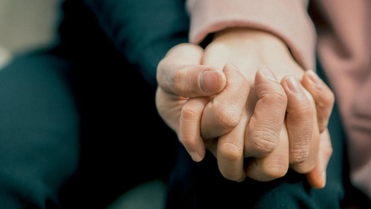 Couple assis côte à côte, se tenant la main dans un moment de complicité