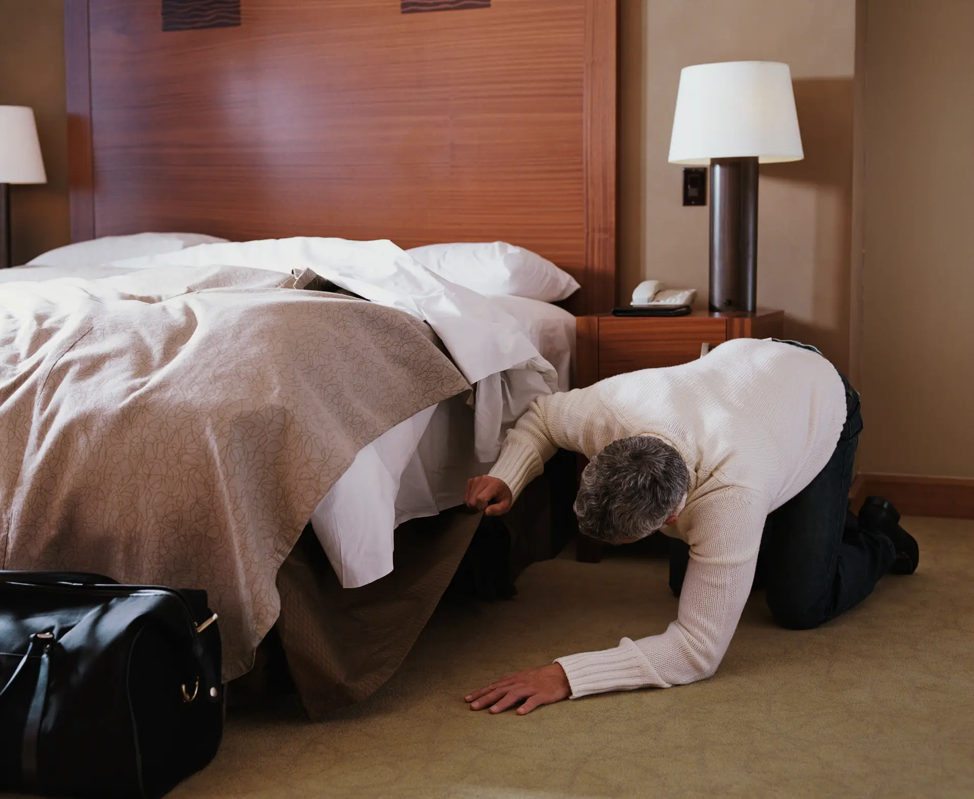 Femme vérifiant sous un lit d'hôtel surélevé