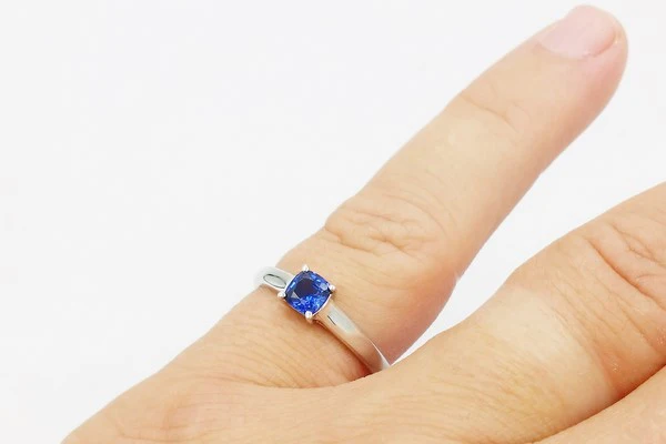 Bague sertie d'un saphir portée sur l'auriculaire d'une femme