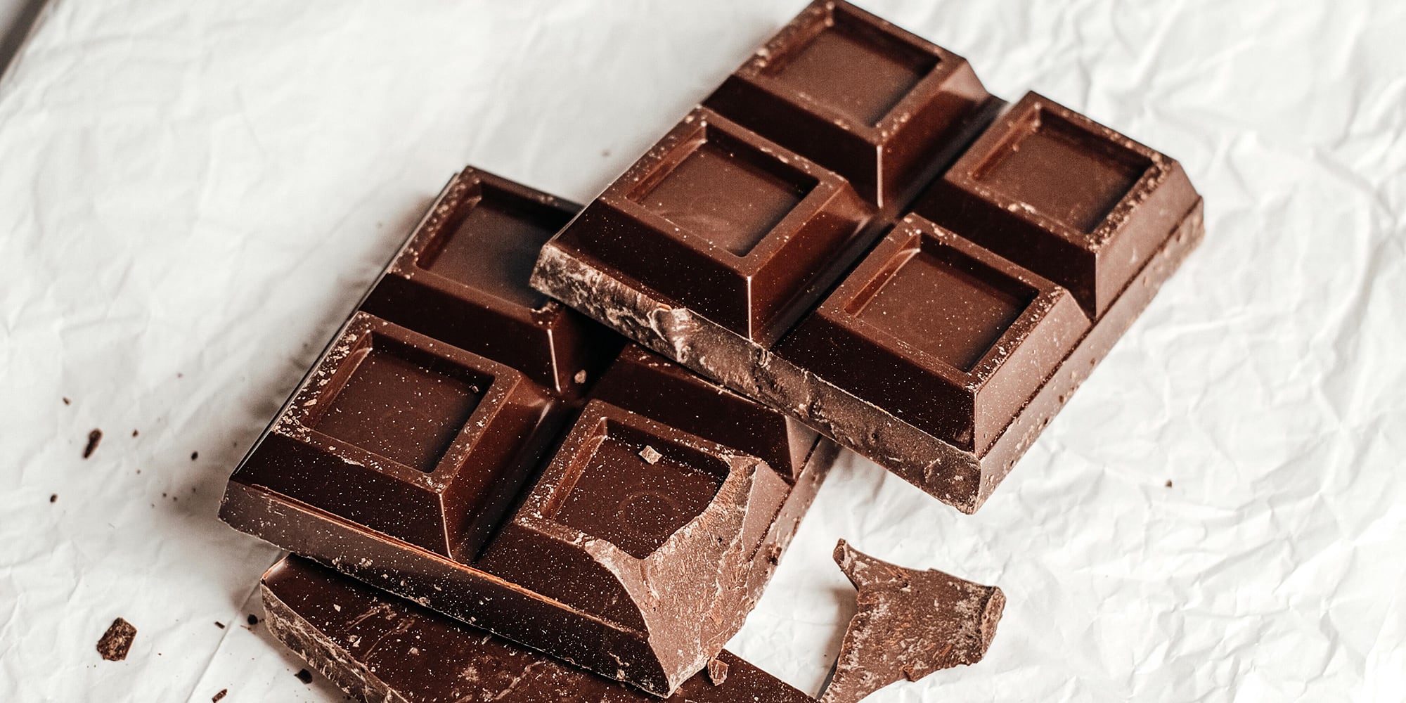 Tablette et carrés de chocolat noir cassés, mettant en avant leur texture et leur couleur foncée.