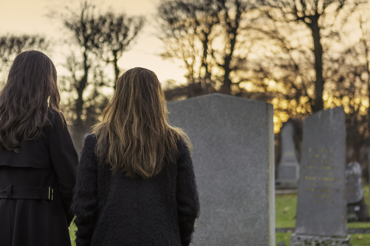 Personne se recueillant devant une tombe fleurie