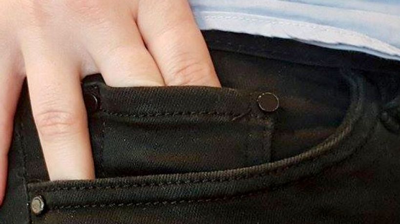 Main glissant une pièce dans la petite poche d'un jean