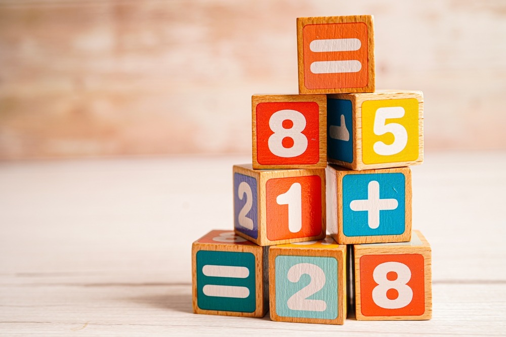 Feuille de papier avec le calcul écrit au crayon, et une main pointant la multiplication