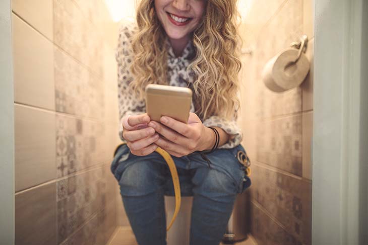 Jeune femme dans les toilettes avec le téléphone 