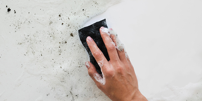 Personne nettoyant un mur avec une brosse et un produit