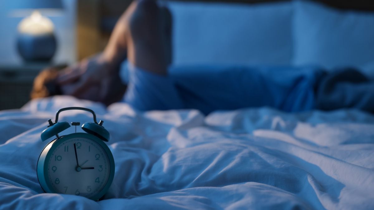 Femme regardant l'heure sur son réveil en pleine nuit