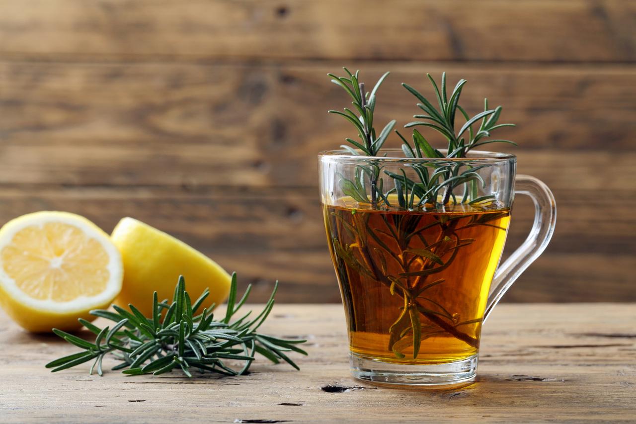 Tasse d'infusion de romarin fumante, posée sur une table en bois